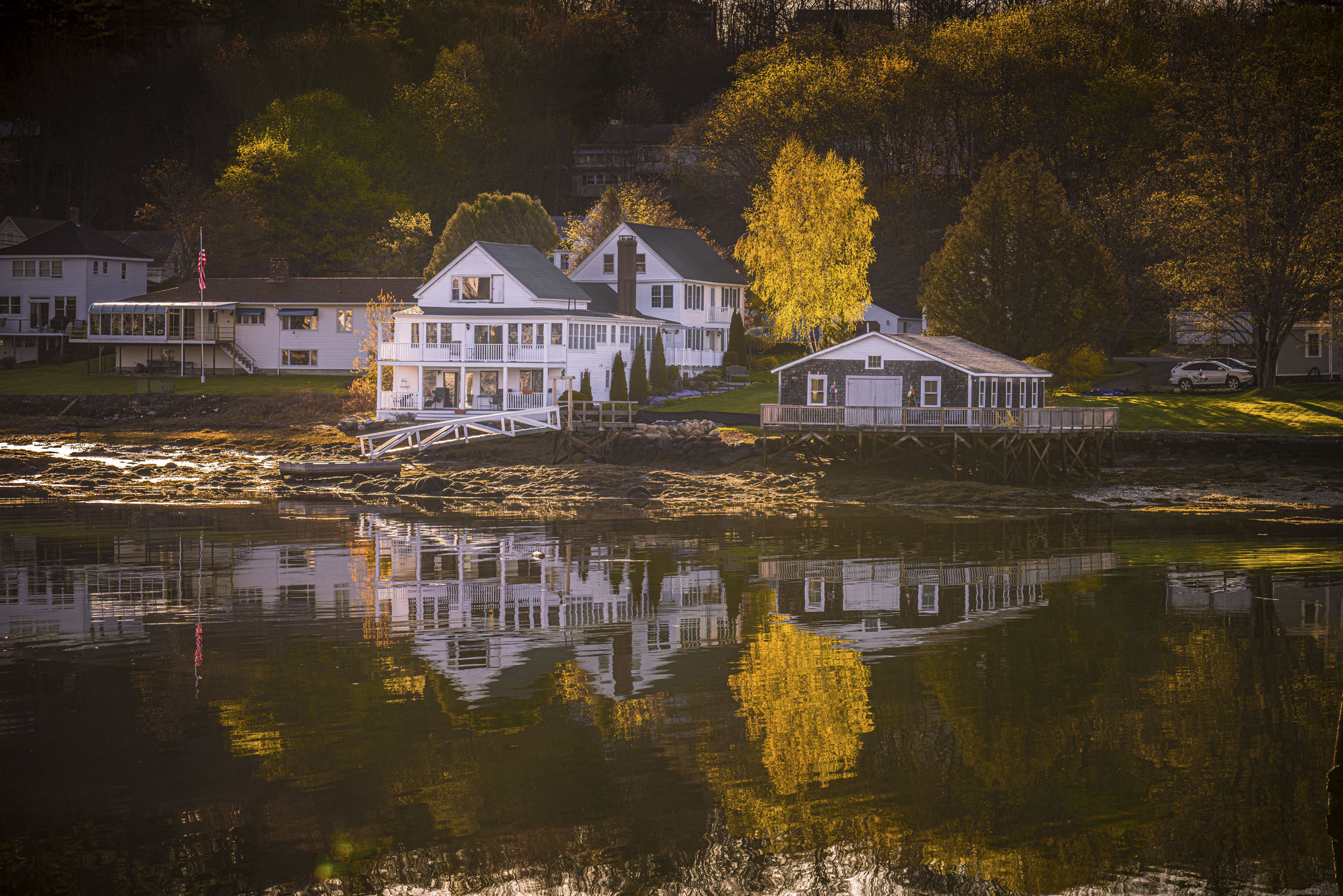 houses and autumn trees reflecting in water; Boothbay Harbor, Maine