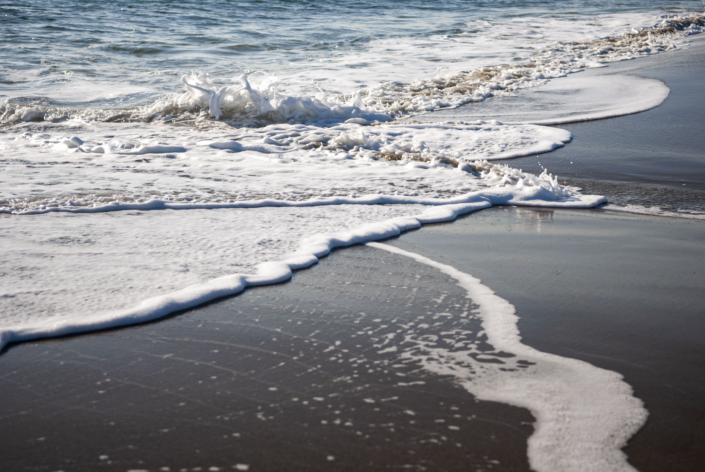 white foam of a wave receeding from a beach