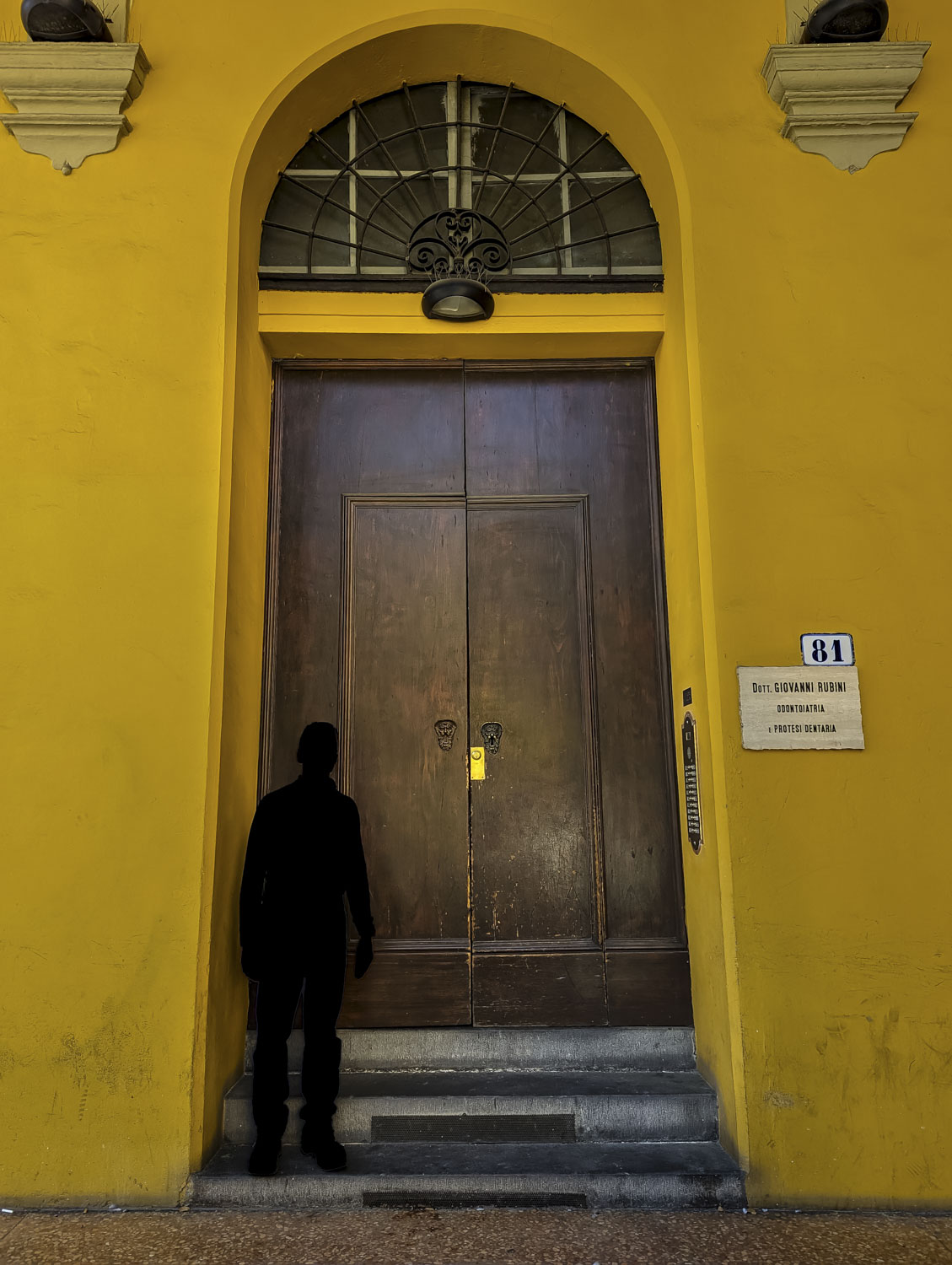 A very large door with the sillhouette of a man in Italy