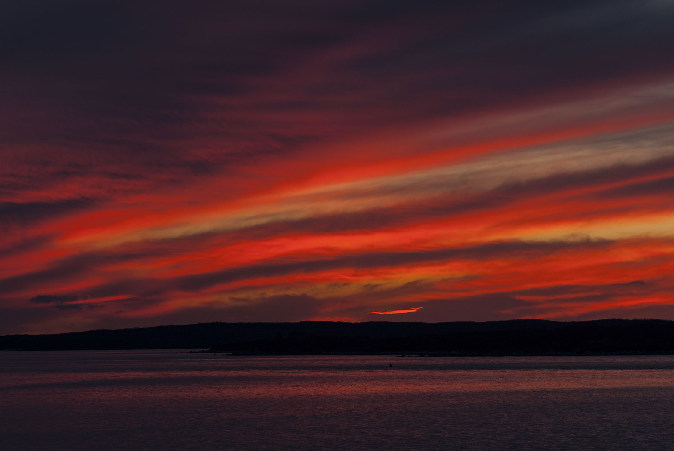 A brilliant red sky that reflects in some slightly choppy water