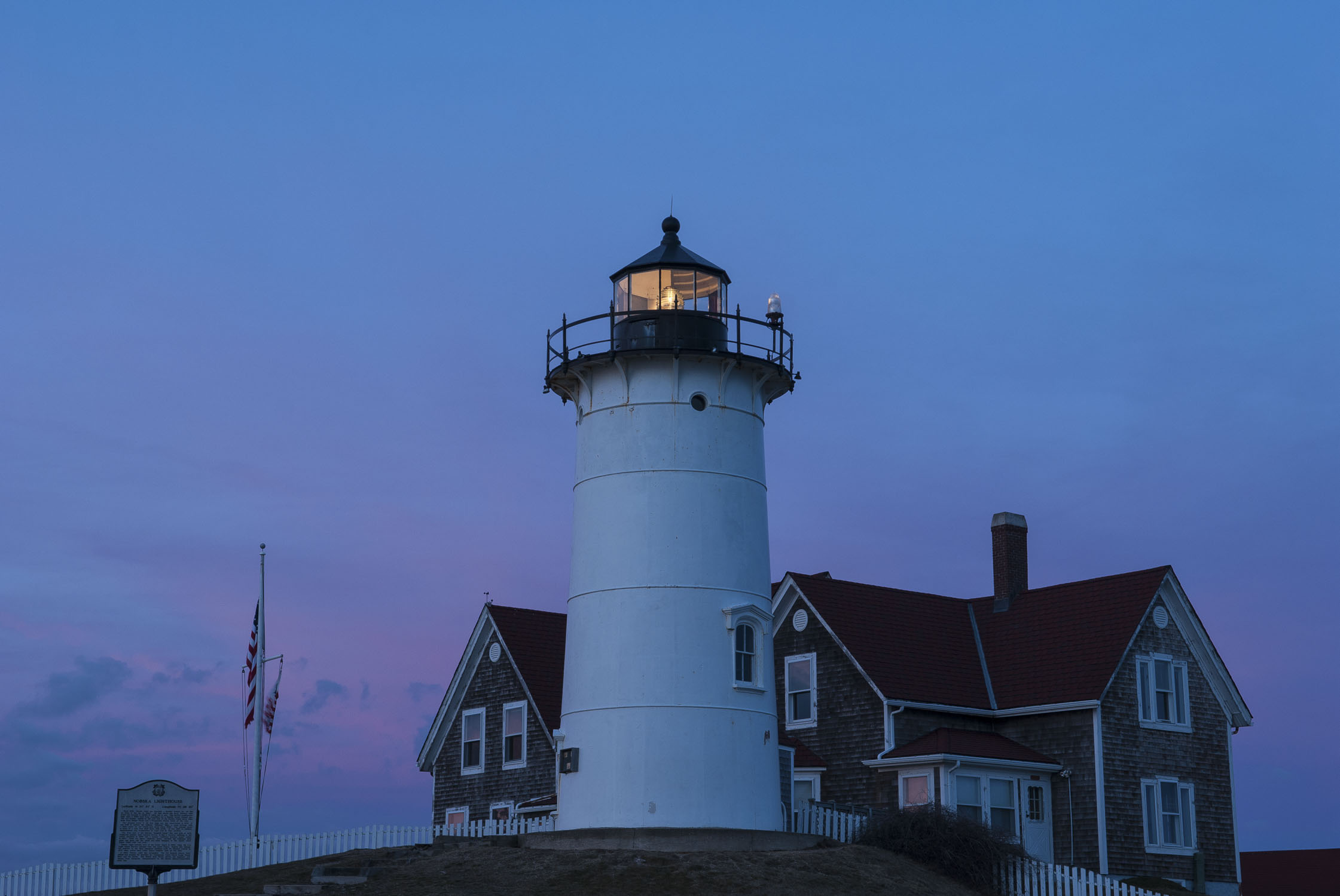 A lighthouse with a blue and pink sky behind it