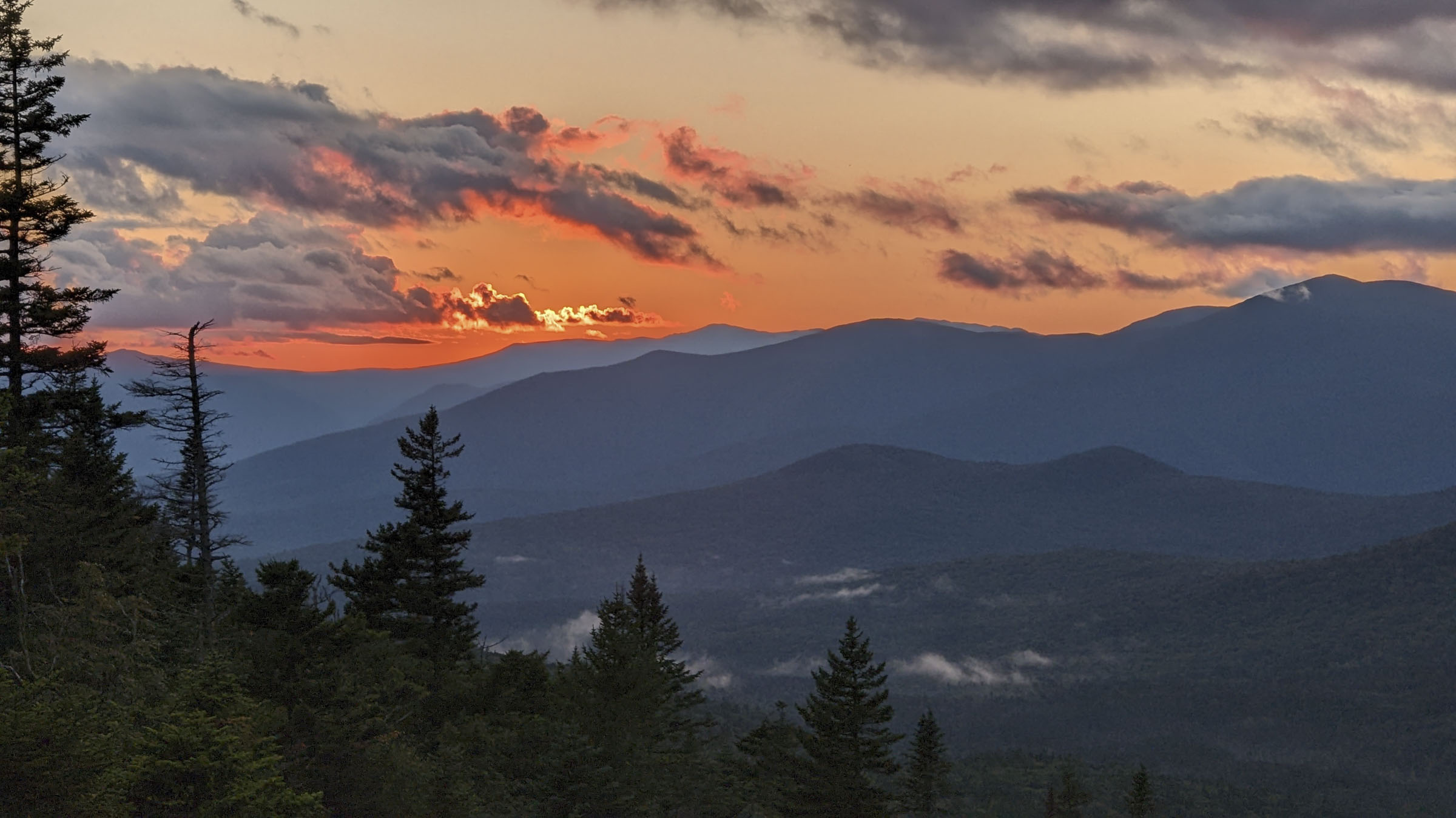 Mountains in front of an orange sky with clouds