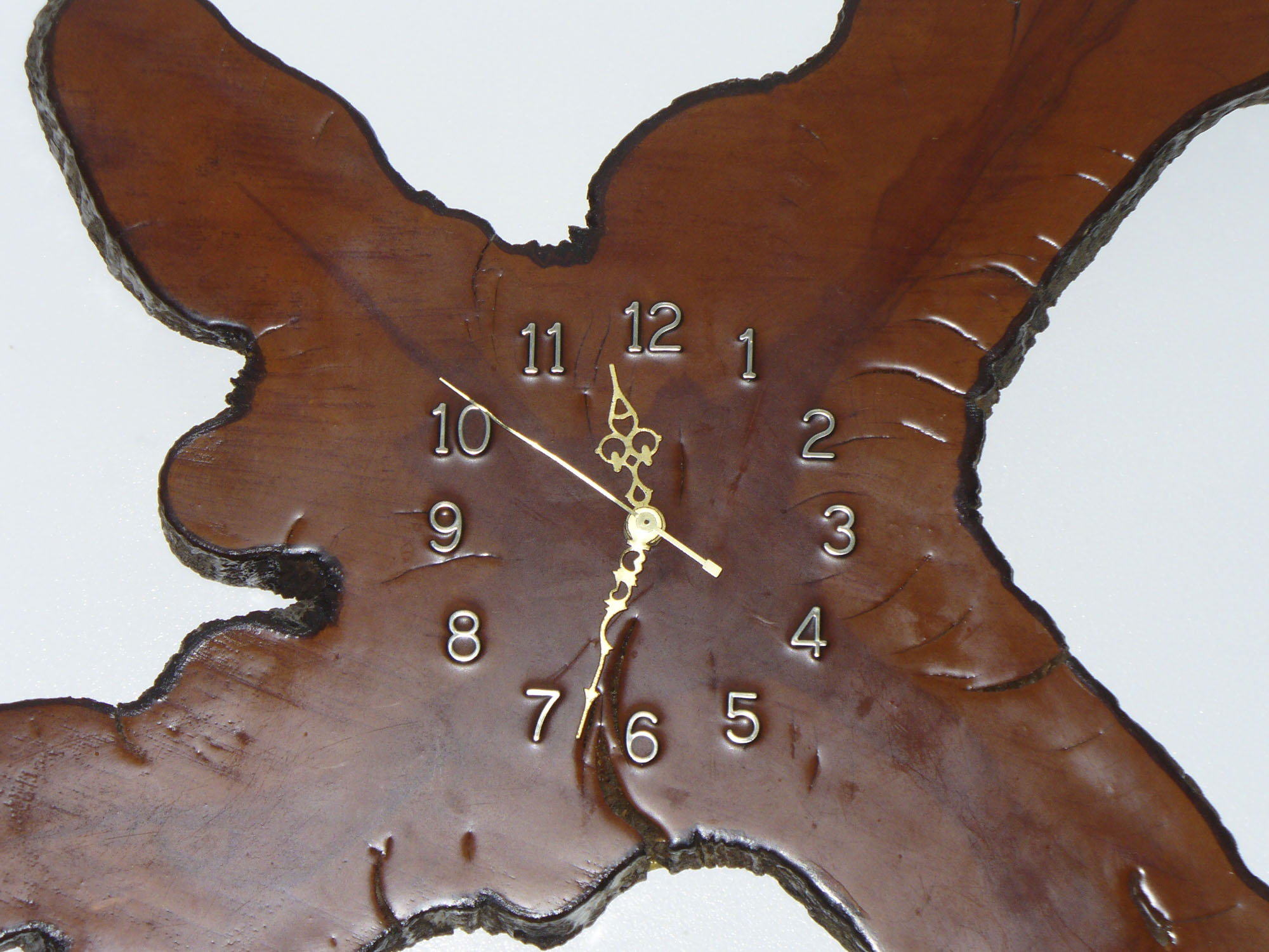 A clock on a uniquely shaped piece of wood.