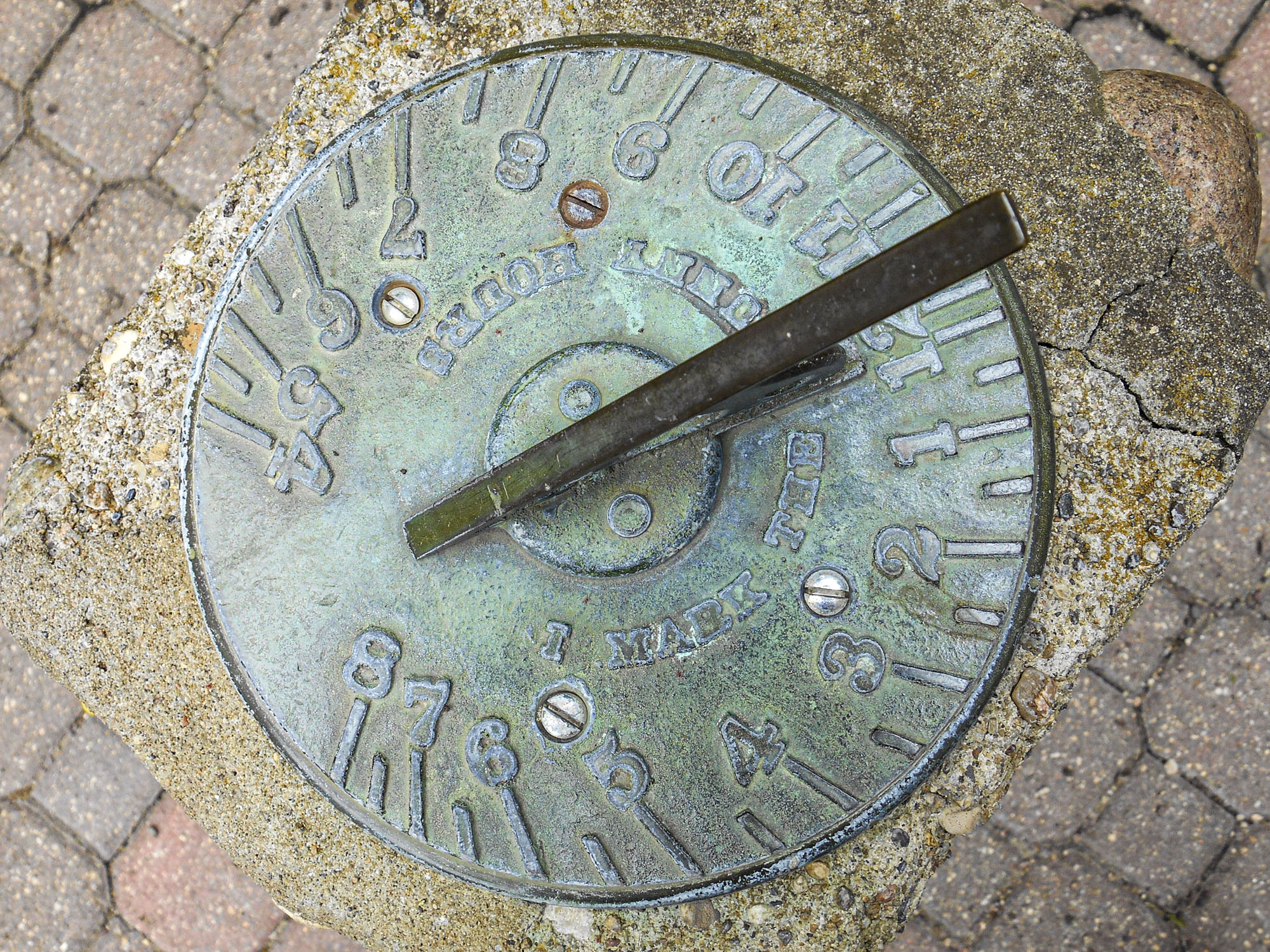 A sundial embedded into the ground, with writing that states I Mark the Sunny Time.