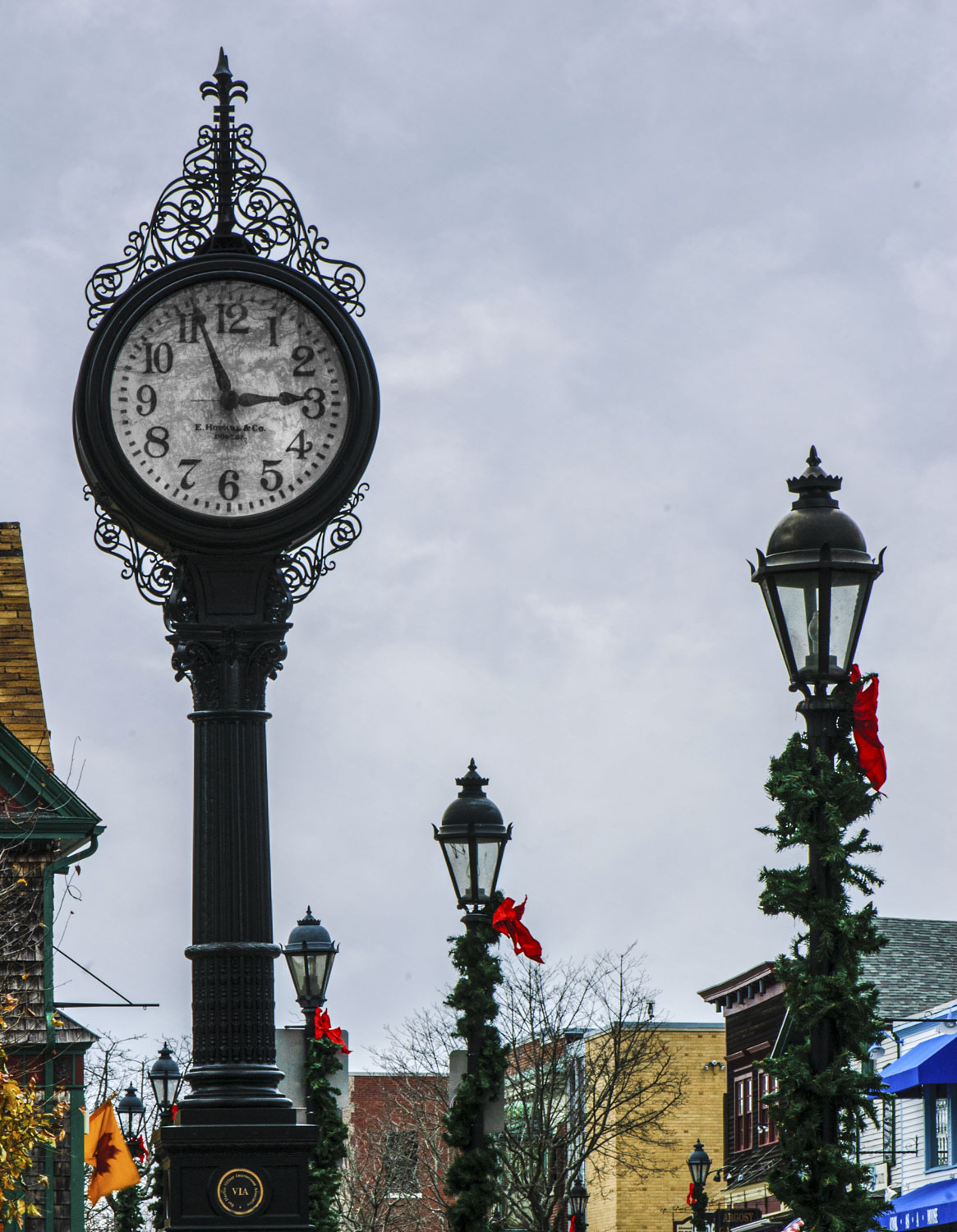 A clock in an ornate metal pole on a wintery street.