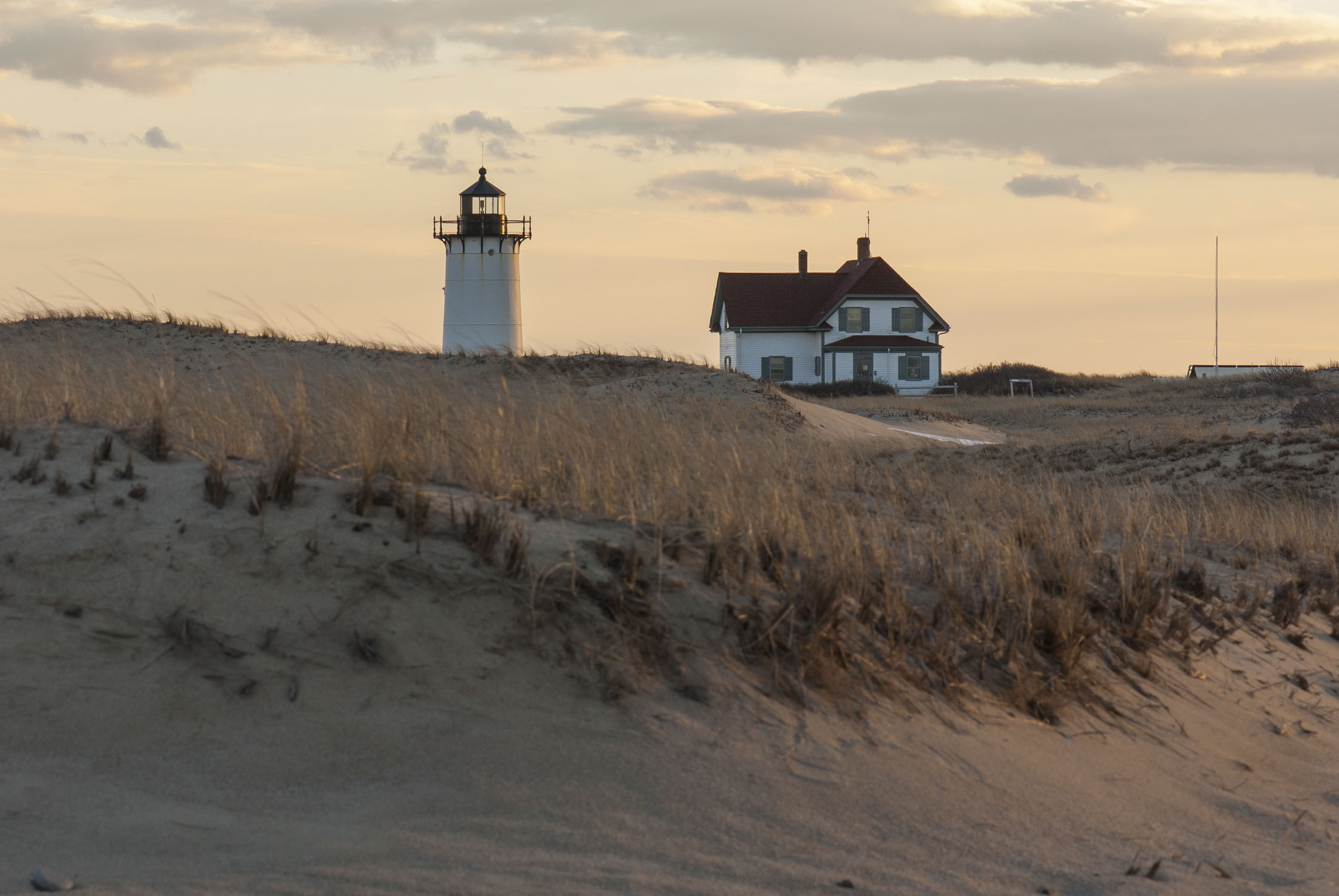 A lighthouse rises from sand dunes