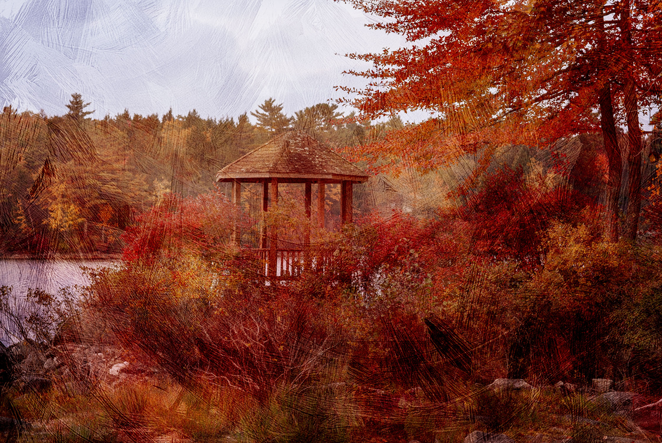 Gazebo with red leaves around it and water behind it