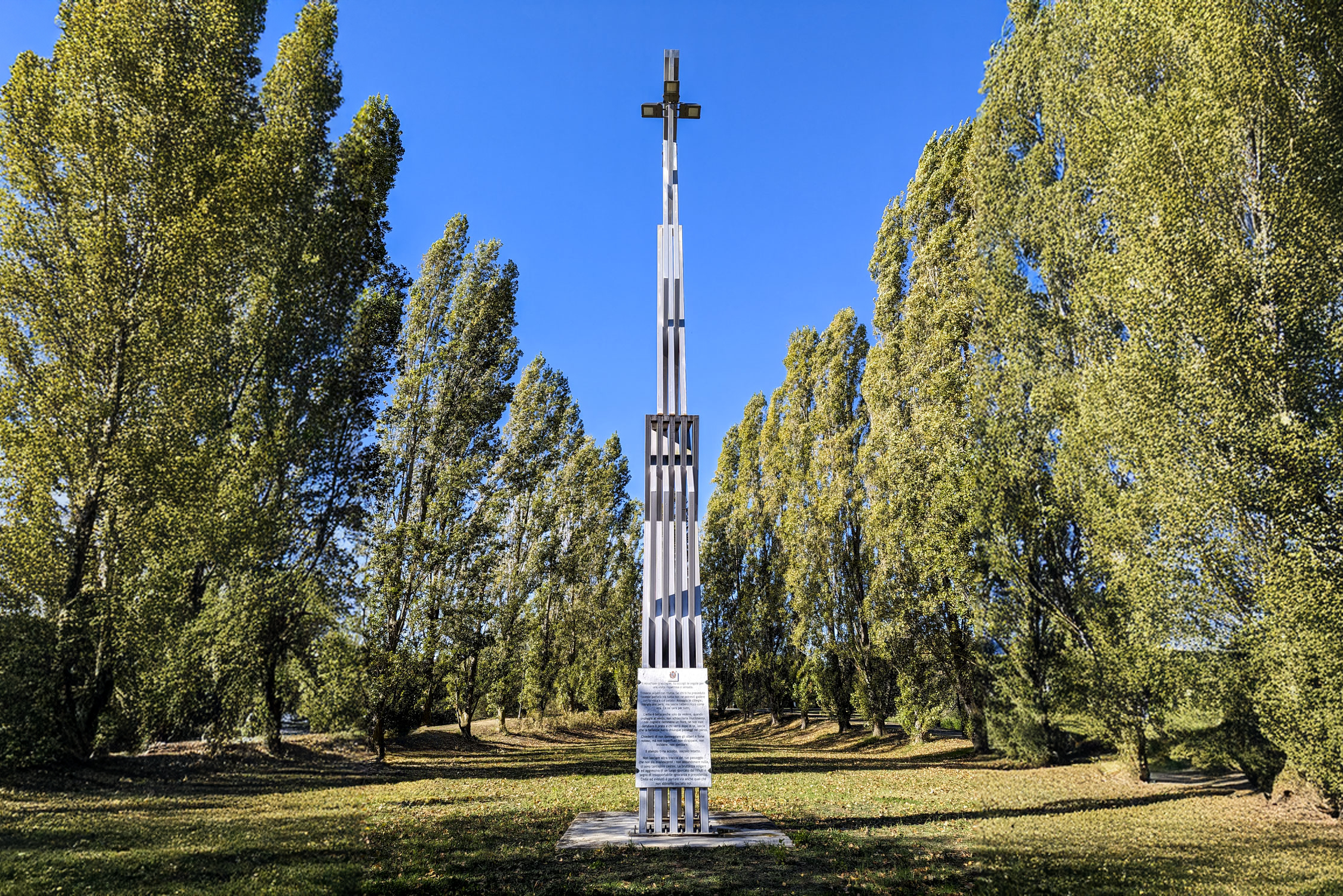 A metal lightpost that is surrounded by tall slim trees