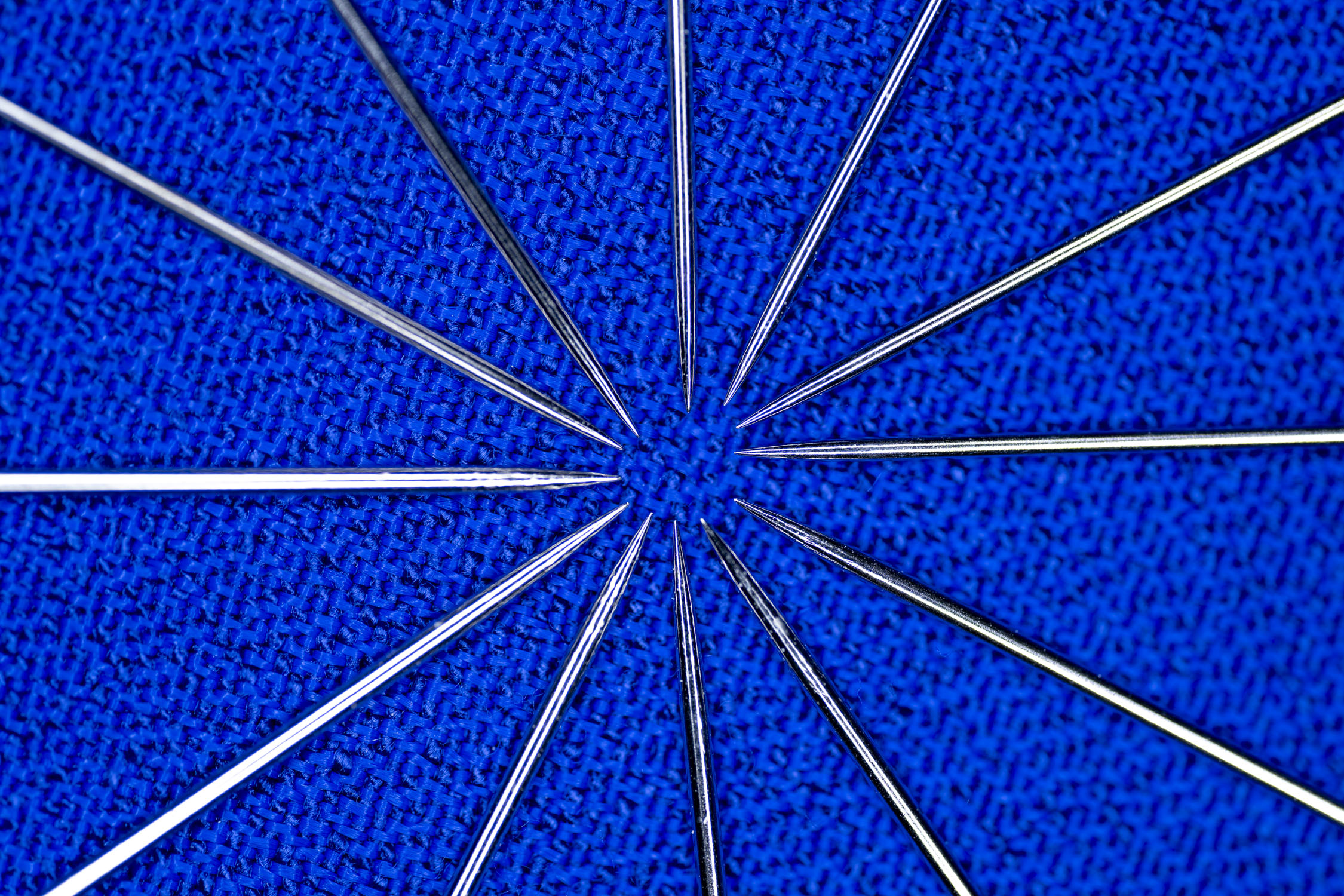 Sewing needles in a circle, all pointed towards the center