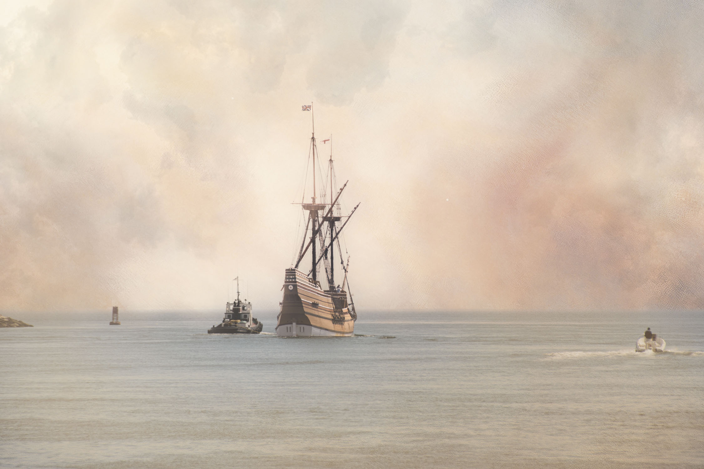 Mayflower II being towed on calm water, with a small tugboat beside it and a tiny motorboat off to the right under a softly textured sky.