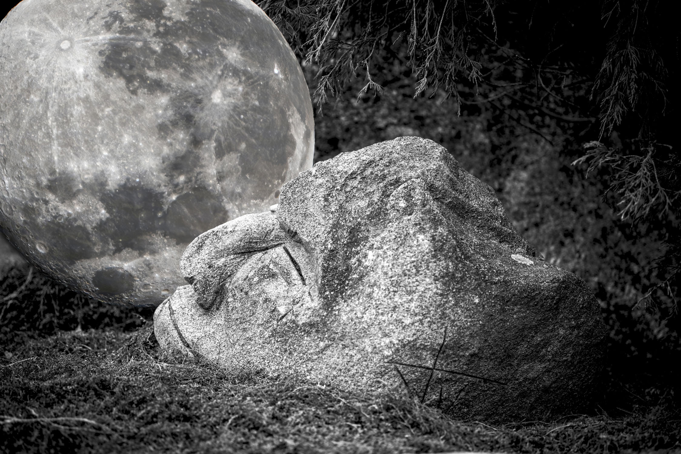 Stone face sculpture with the moon behind it