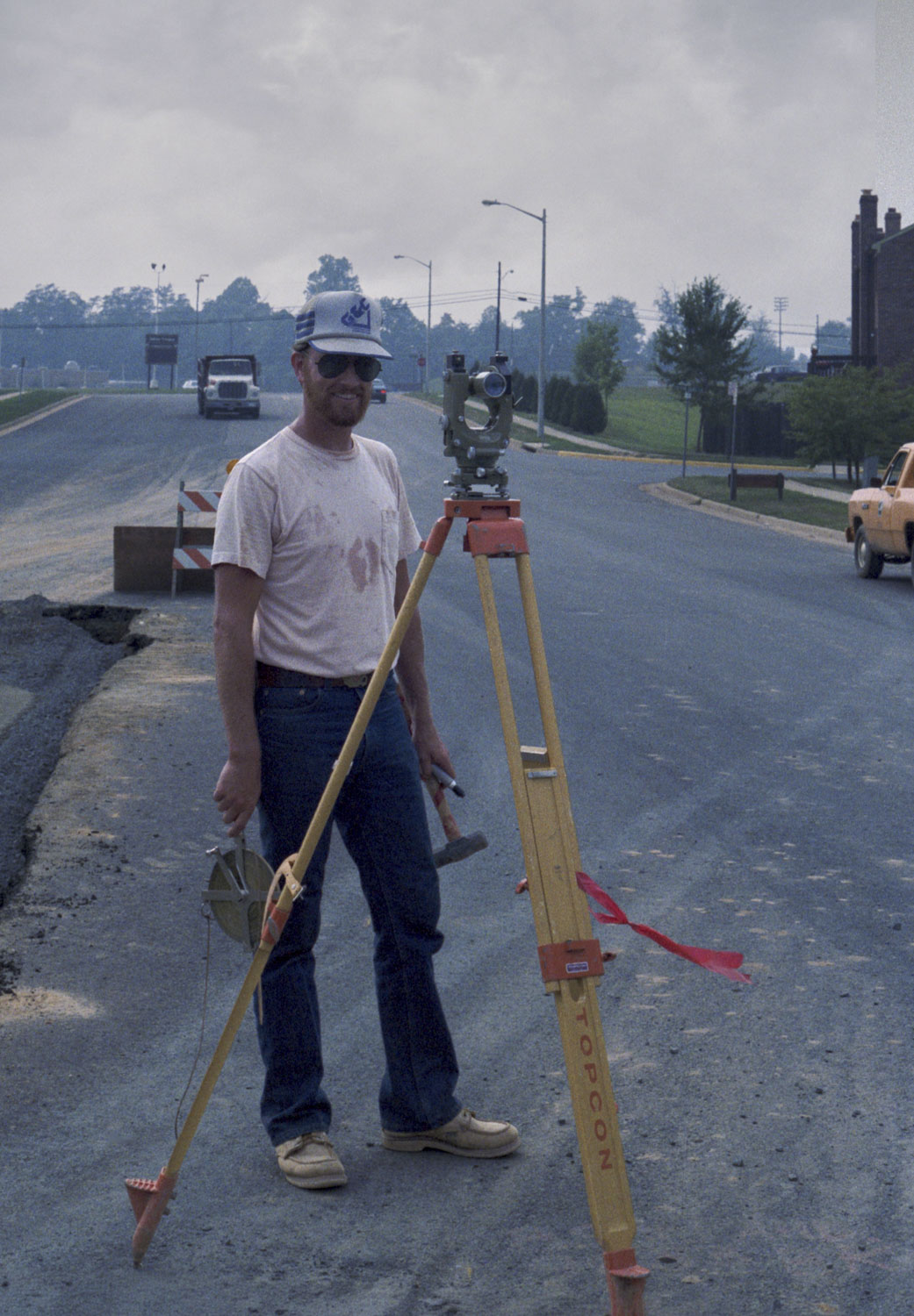 A surveyor is standing on a road