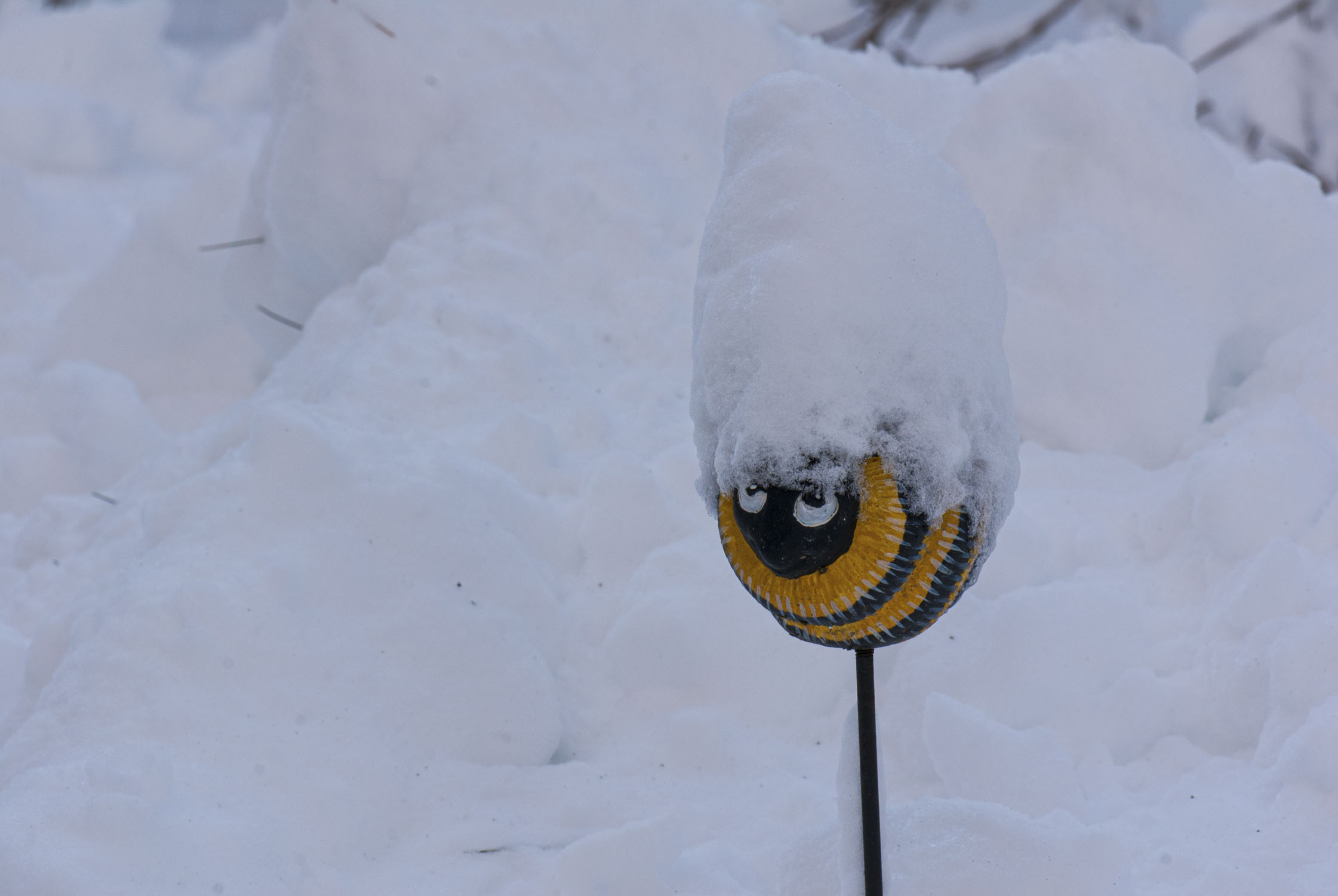 A garden decoration of a bee on a post covered with snow